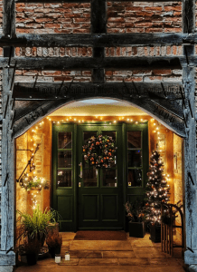 Photo of green wooden door with a Christmas wreath and lights | luxury homes by brittany corporation