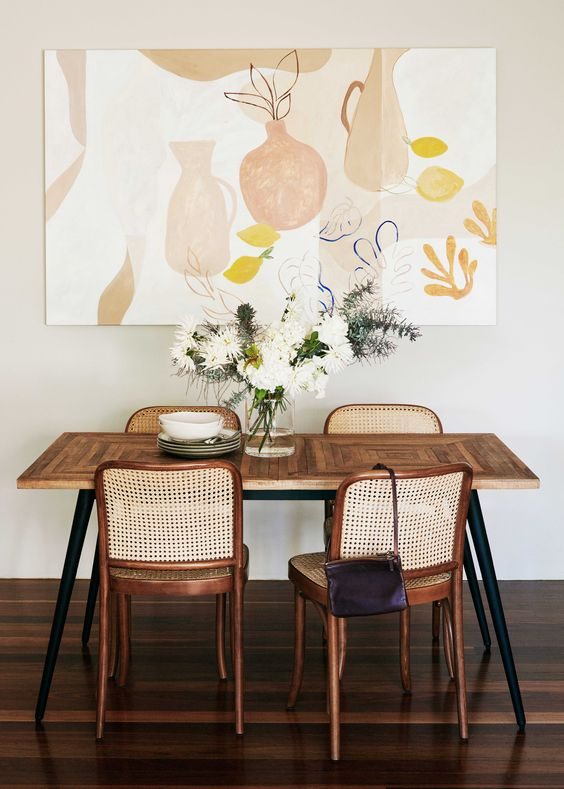 Rattan dining chairs and a minimalist painting on the wall