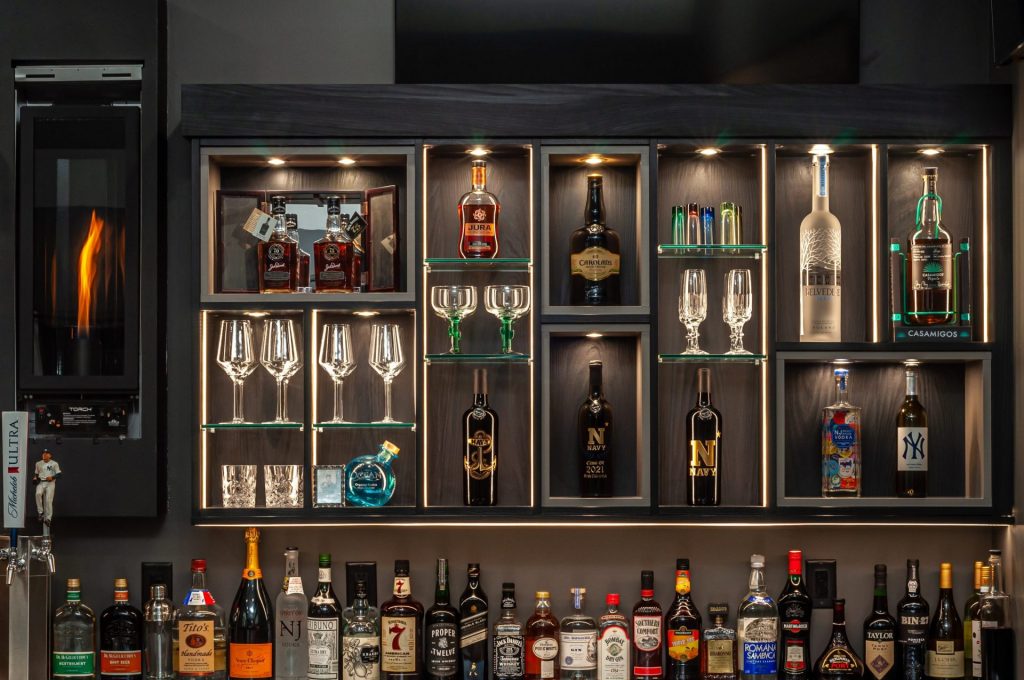 Bottles of alcoholic beverages and bar essentials stocked up in a brown shelf.