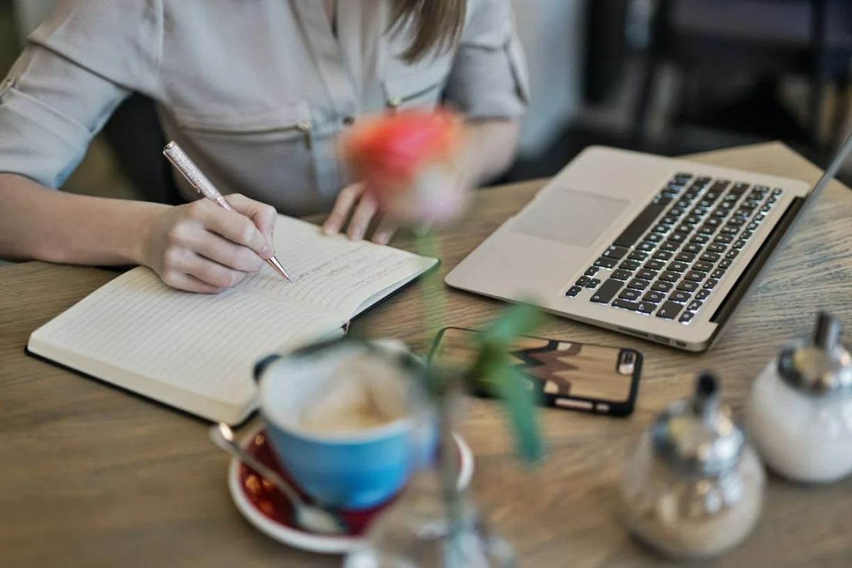 Photo of a woman writing on a notebook