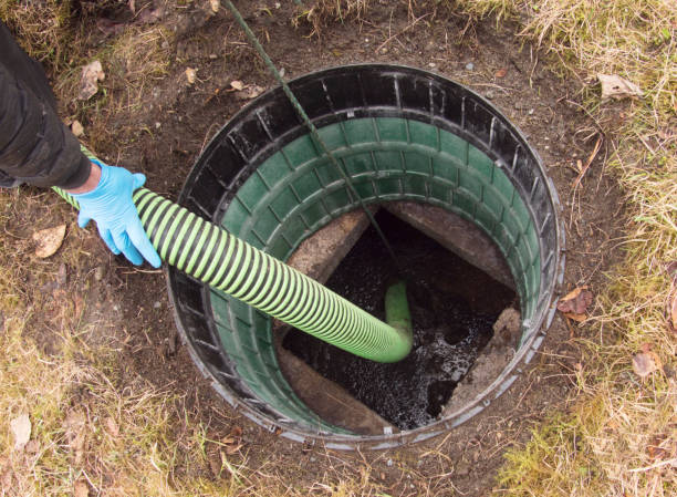 Hose pumping out home septic tank through an access riser.